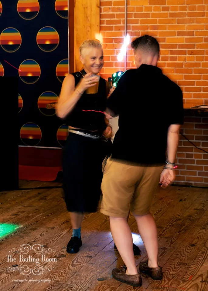 Two guests dancing in front of the rainbow backdrop at Dirty Tea