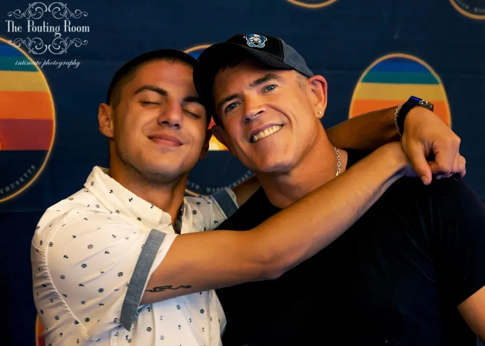 Two guests hugging for a photo at the Dirty Tea backdrop
