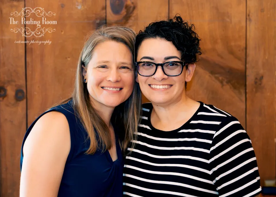 Two guests smiling together against the wood wall at Dirty Tea