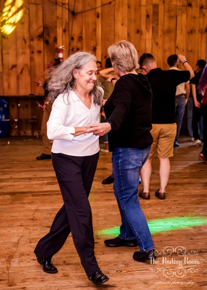 Two guests dancing hand in hand on the wooden floor at Dirty Tea