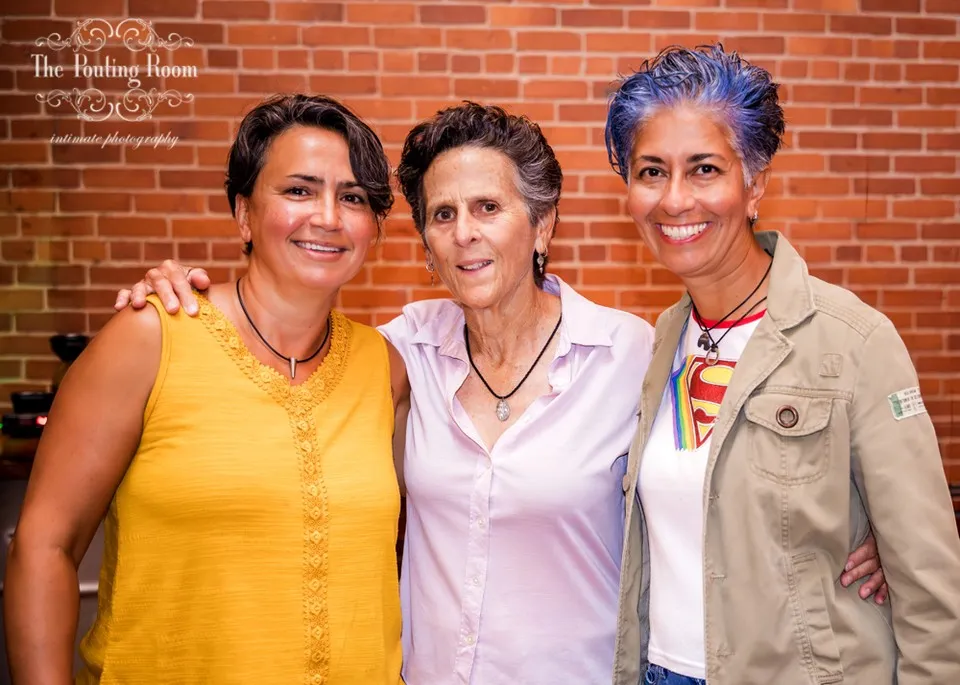 Three friends arm in arm in front of the brick wall at Dirty Tea