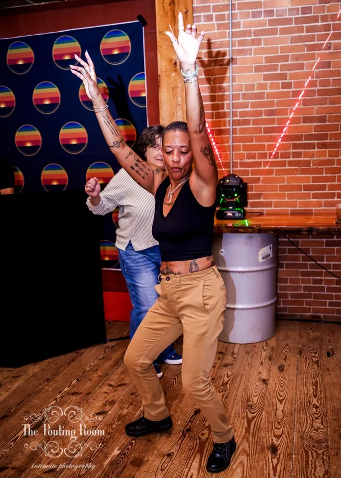 Two guests dancing in front of the rainbow backdrop at Dirty Tea