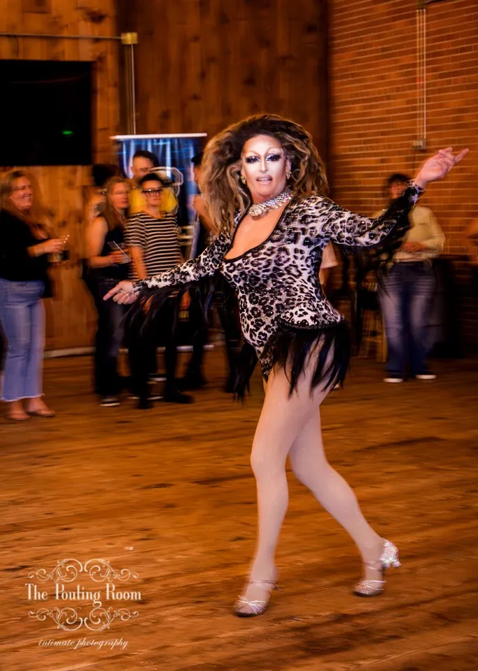 A drag performer mid-routine with arms outstretched at Dirty Tea