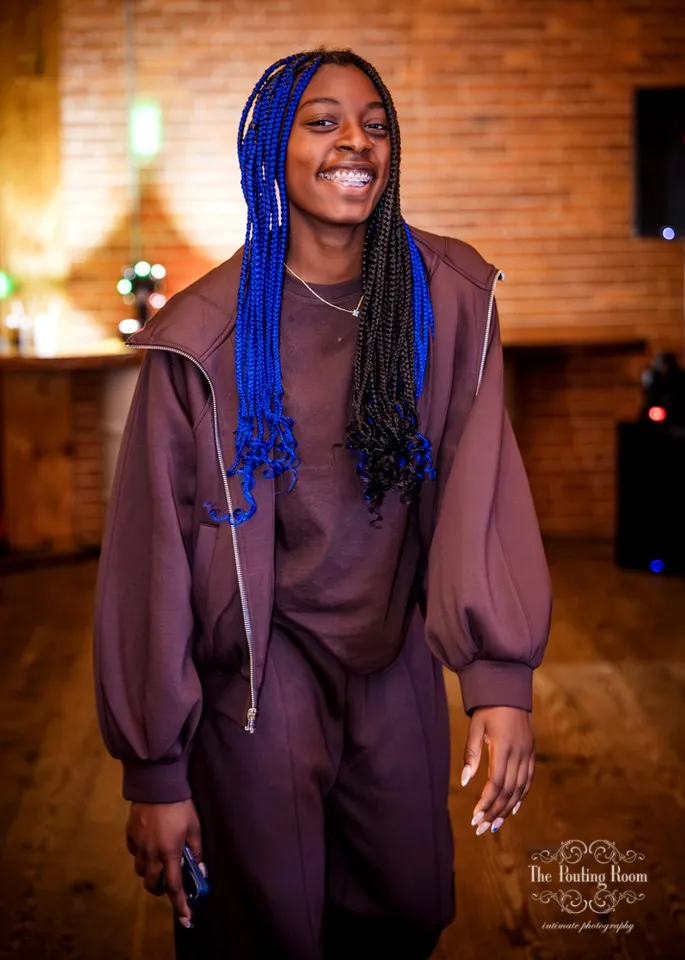 A guest smiling in front of the brick wall at Dirty Tea