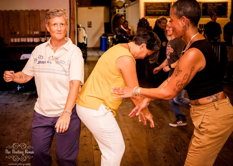 Three guests dancing low to the floor in the tasting room at Dirty Tea