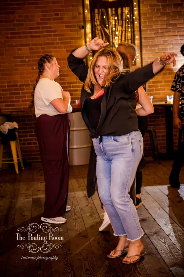 A dancer with both arms overhead singing along at Dirty Tea
