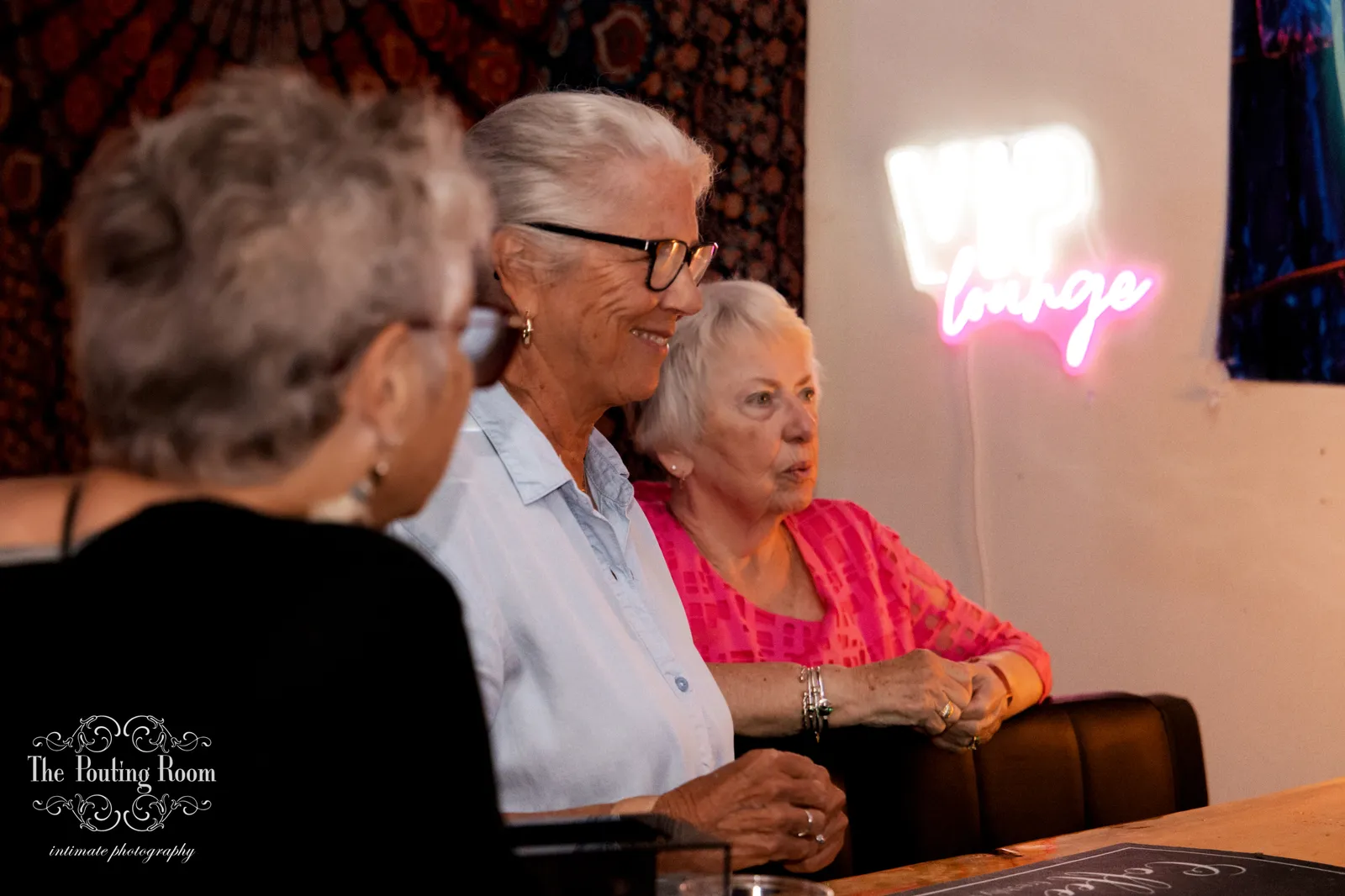 Guests relaxing in the VIP lounge beneath the neon sign