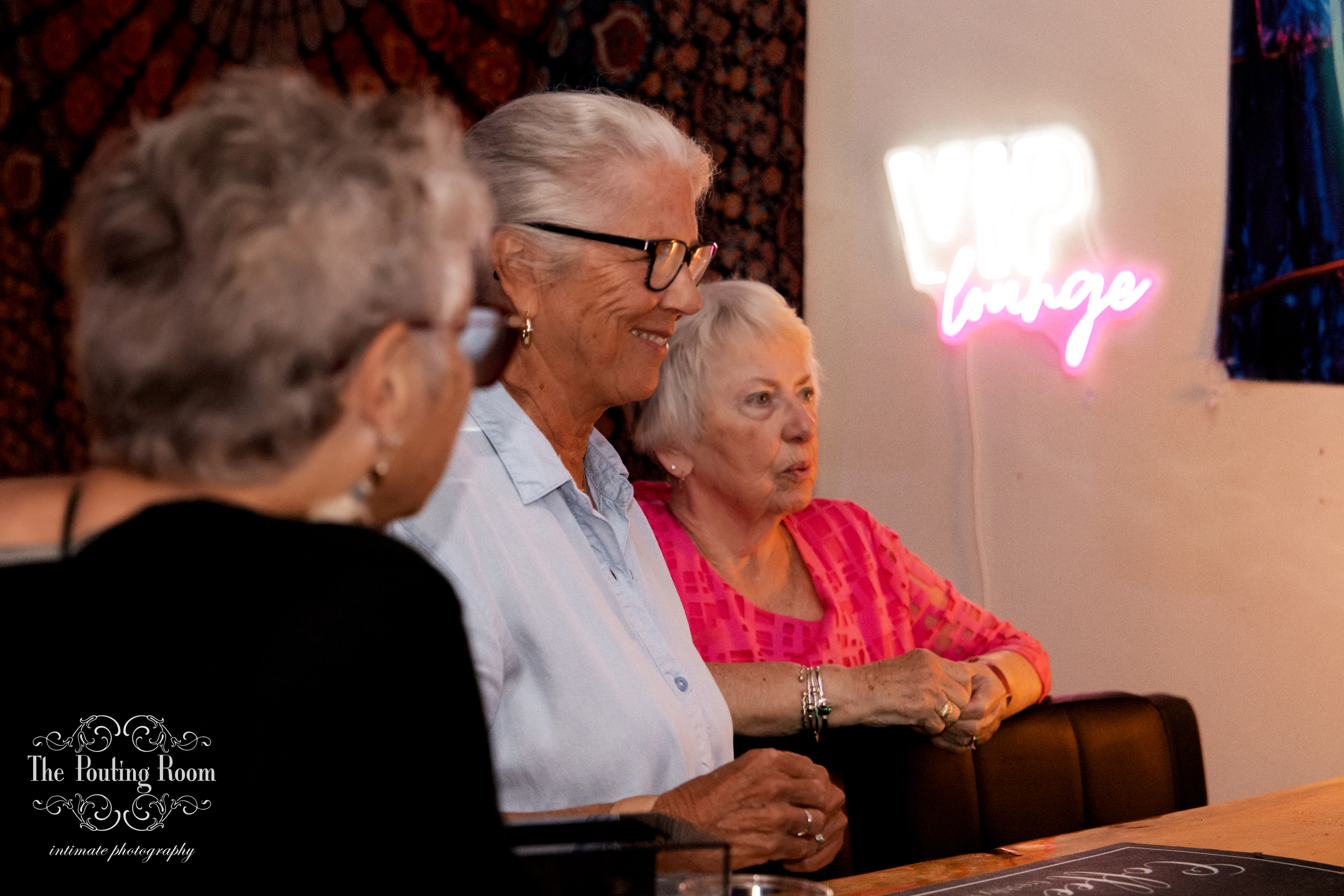 Guests relaxing in the VIP lounge beneath the neon sign