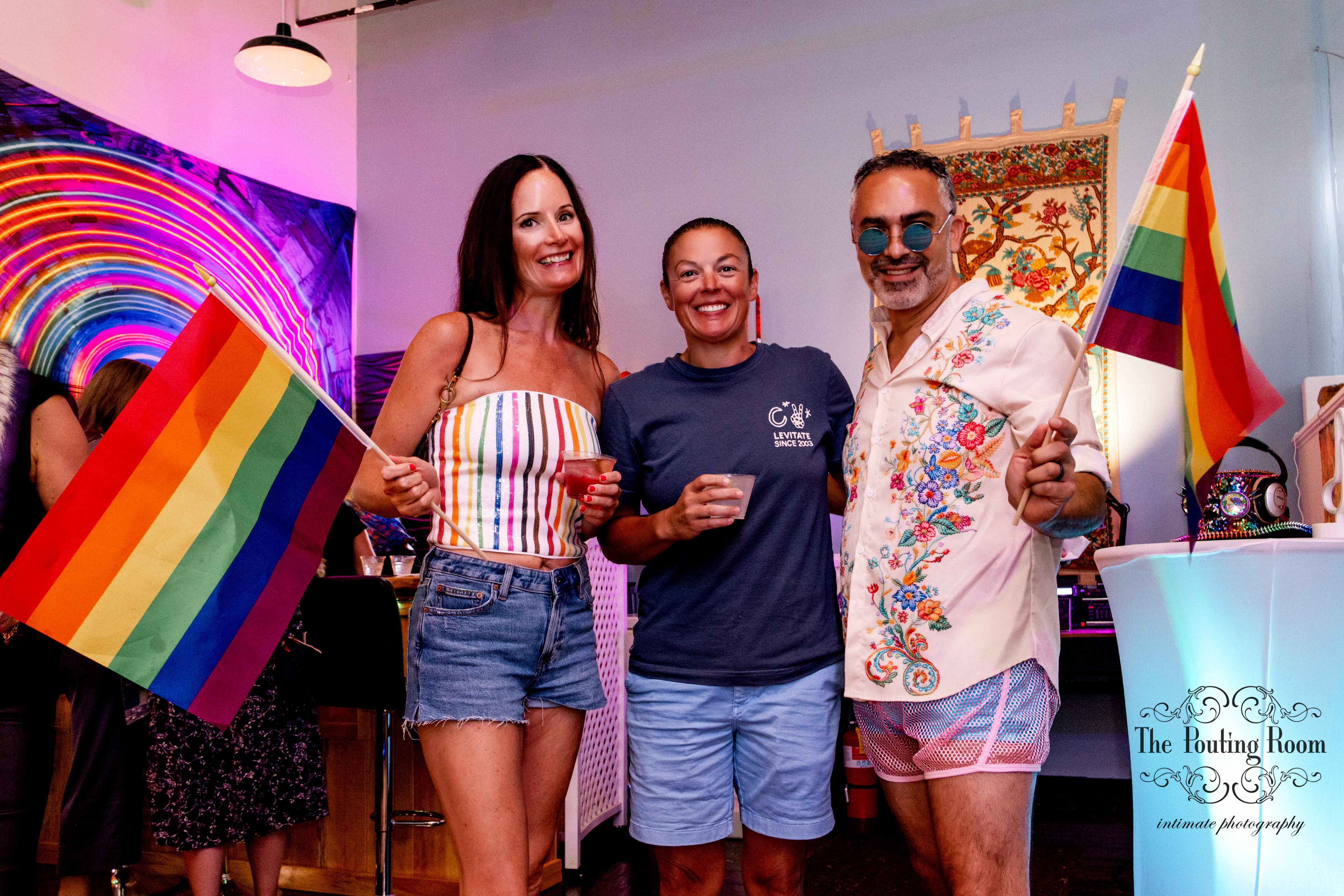 Friends waving Pride flags at the Inaugural Tea Dance